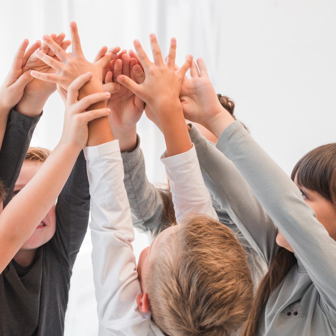 Kinder strecken ihre Hände nach oben und bilden einen Kreis aus verschiedenen Körpern.